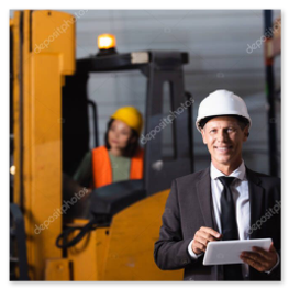 Wózek widłowy czołowy pracujący między regałami magazynu