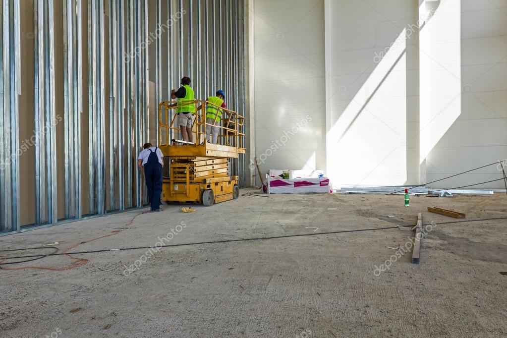 Elektryczny podest nożycowy Haulotte pracujący w magazynie